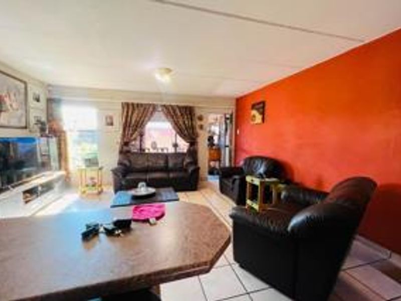 Open plan living area featuring tiled flooring and a built-in breakfast bar, providing a functional space for daily living.