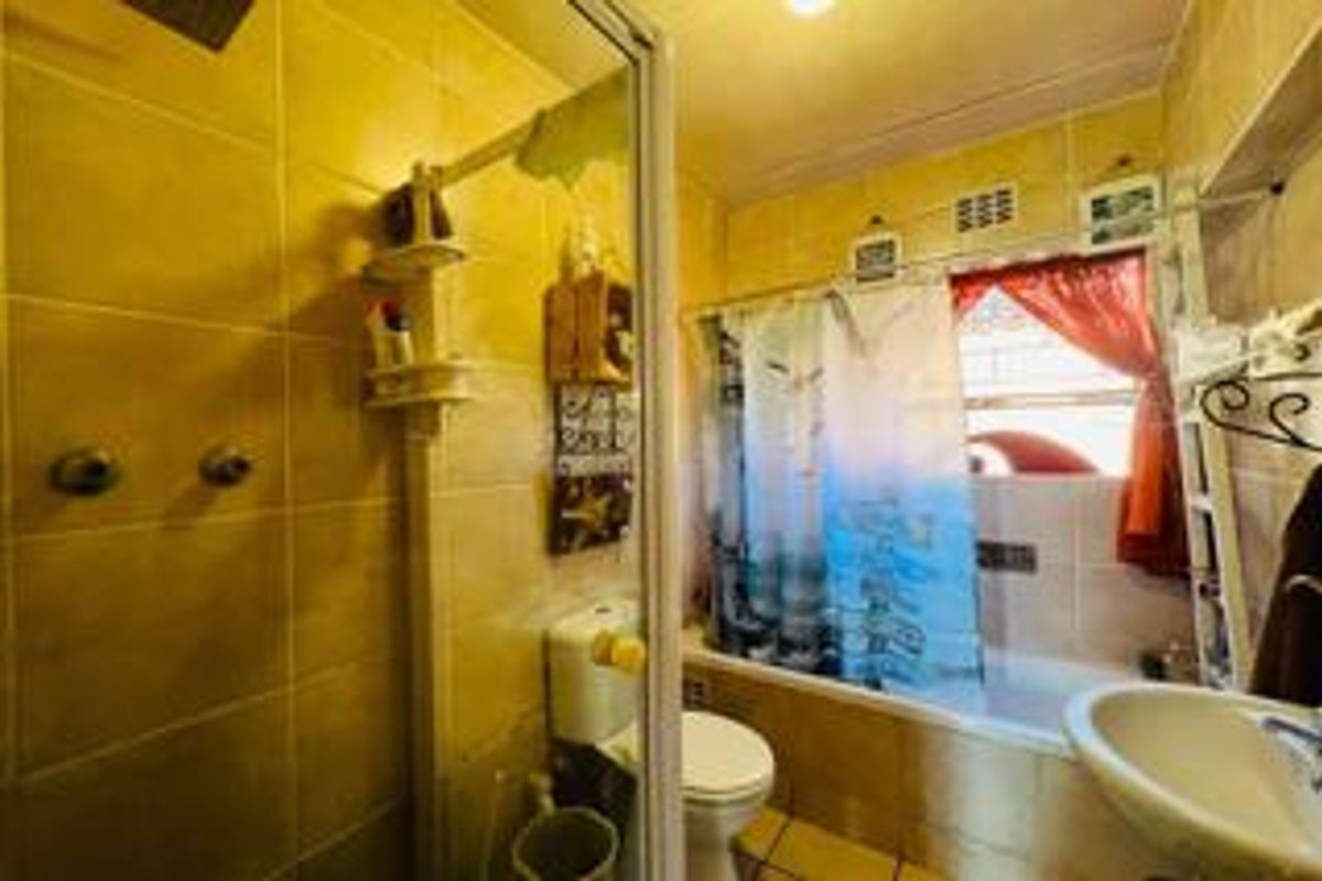 A functional bathroom featuring a shower enclosure, bathtub, toilet, and pedestal basin with tiled finishes throughout.