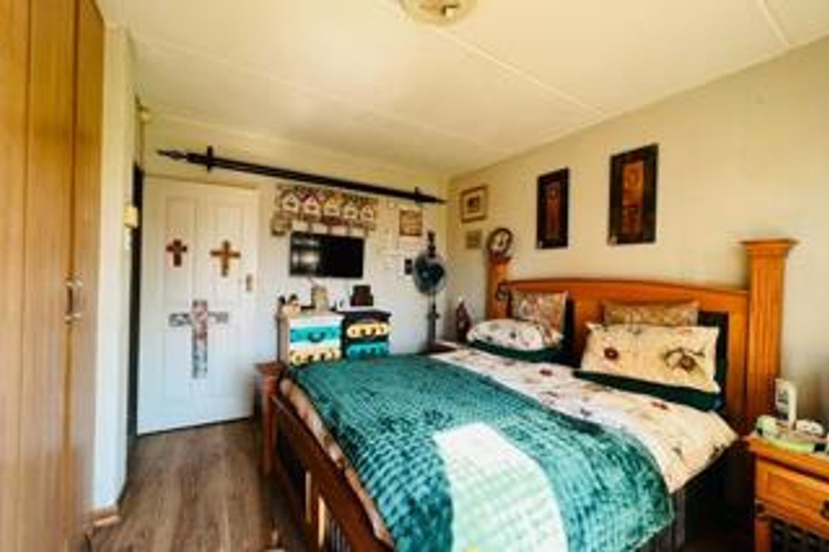 A functional bedroom featuring laminate flooring and a built-in wardrobe, offering a comfortable and practical living space.
