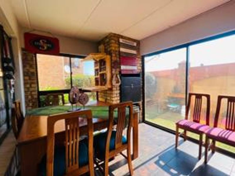 Enclosed patio area featuring a built-in braai, tiled flooring, and large sliding glass doors providing access to the rear garden.
