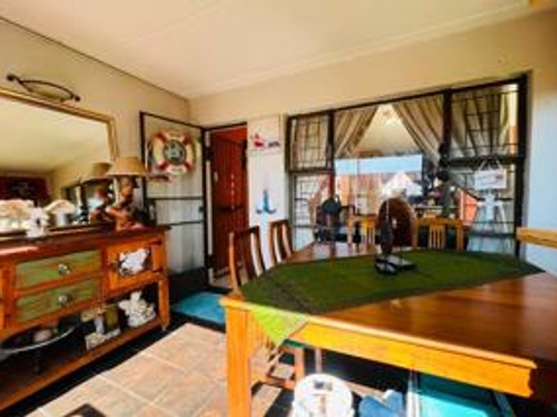 A dining area featuring tiled flooring and large windows with security bars, providing natural light and access to the exterior.