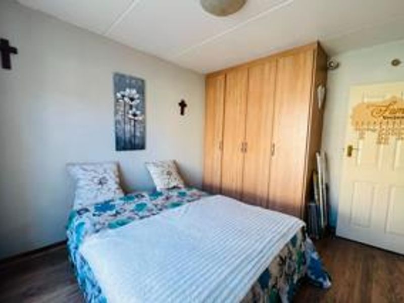 A functional bedroom featuring laminate flooring and a large built-in wooden wardrobe providing ample storage space.