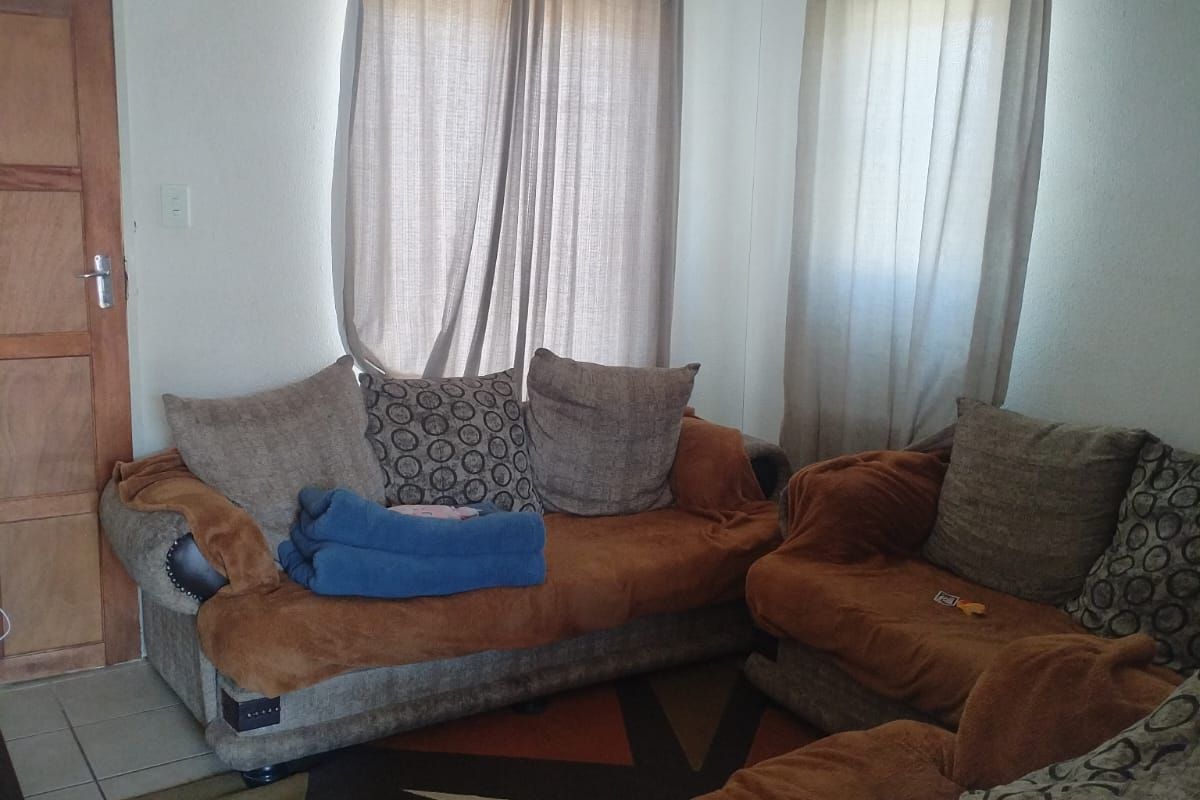 A living room area featuring tiled flooring and a timber door, providing a functional space for relaxation.
