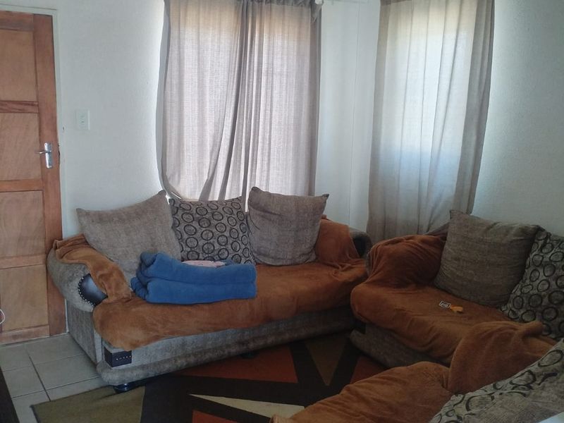 A living room area featuring tiled flooring and a timber door, providing a functional space for relaxation.