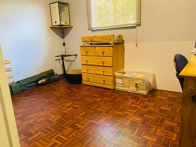 A bedroom featuring classic parquet flooring and venetian blinds, offering a functional space with potential for cosmetic updates.