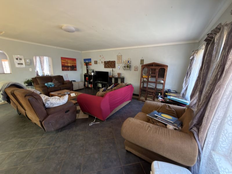 Spacious living room featuring dark tiled flooring and neutral wall finishes, offering a versatile layout for comfortable family living.