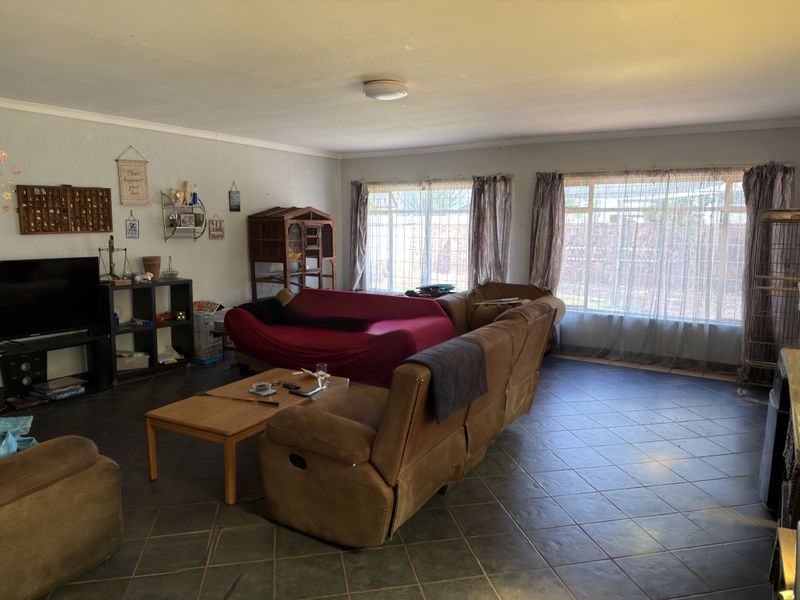 Spacious living room featuring dark tiled flooring and large windows that provide ample natural light, offering a versatile space for relaxation.