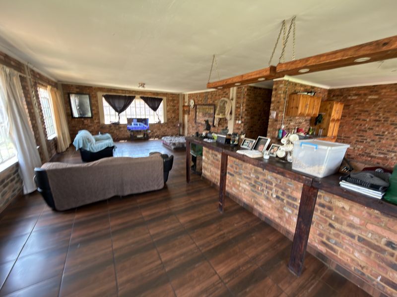Spacious open-plan living area featuring exposed brick walls, tiled flooring, and a built-in timber bar counter, offering a rustic aesthetic with potential for modernization.