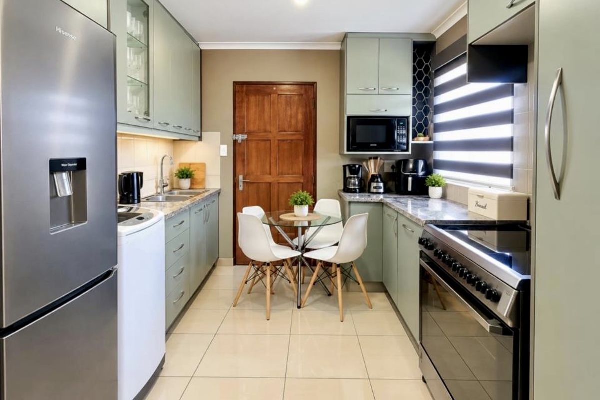 A well-maintained kitchen featuring sage green cabinetry, stone countertops, tiled flooring, and integrated appliances, offering a functional and modern cooking space.
