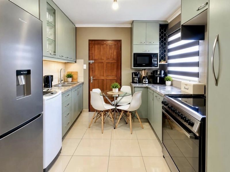 A well-maintained kitchen featuring sage green cabinetry, stone countertops, tiled flooring, and integrated appliances, offering a functional and modern cooking space.