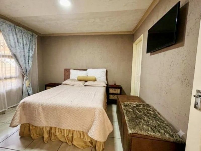 A bedroom featuring tiled flooring, textured walls, and recessed ceiling lighting, providing a functional space with potential for cosmetic updates.