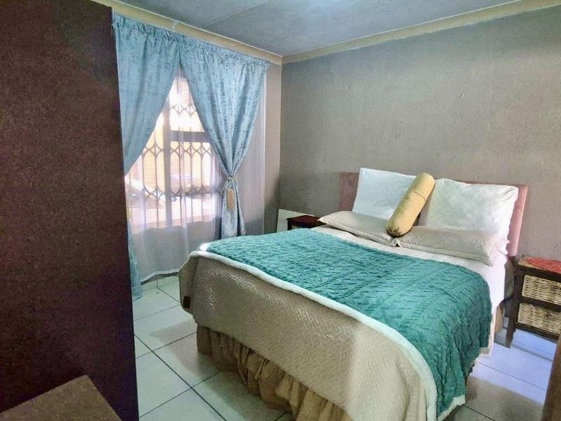 A bedroom featuring tiled flooring and a window with security gate, requiring cosmetic updates to the walls and ceiling to improve overall appeal.