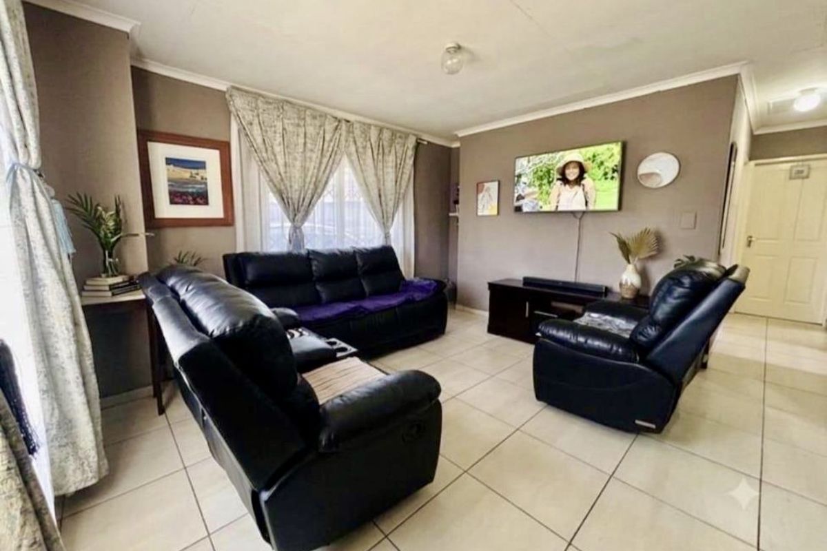 A comfortable living room featuring neutral tiled flooring and coved ceilings, providing a functional and well-maintained space for relaxation.
