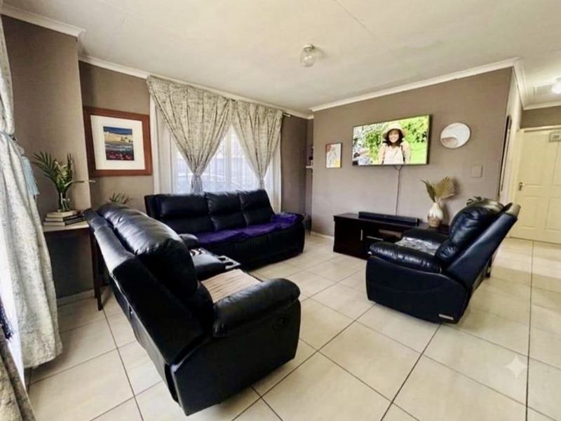 A comfortable living room featuring neutral tiled flooring and coved ceilings, providing a functional and well-maintained space for relaxation.