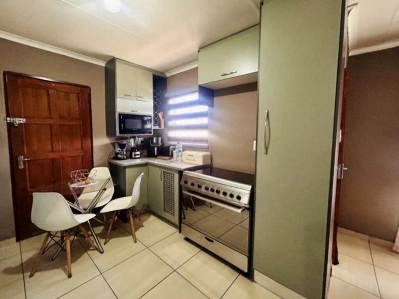 Compact kitchen featuring built-in cabinetry, a freestanding stove, built-in microwave, and tiled flooring, offering a functional layout for daily meal preparation.