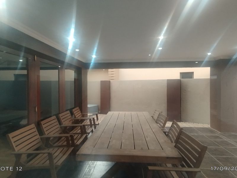 A covered outdoor patio area featuring tiled flooring, recessed ceiling lighting, and large sliding glass doors providing access to the interior.