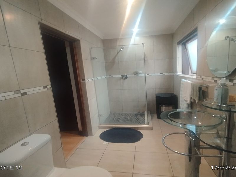A functional bathroom featuring tiled walls and flooring, a glass-enclosed shower, and a modern glass vanity basin.