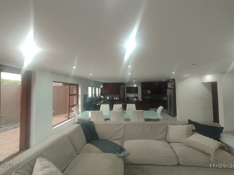 Spacious open-plan living and dining area featuring tiled floors, recessed lighting, and direct access to an outdoor patio space.