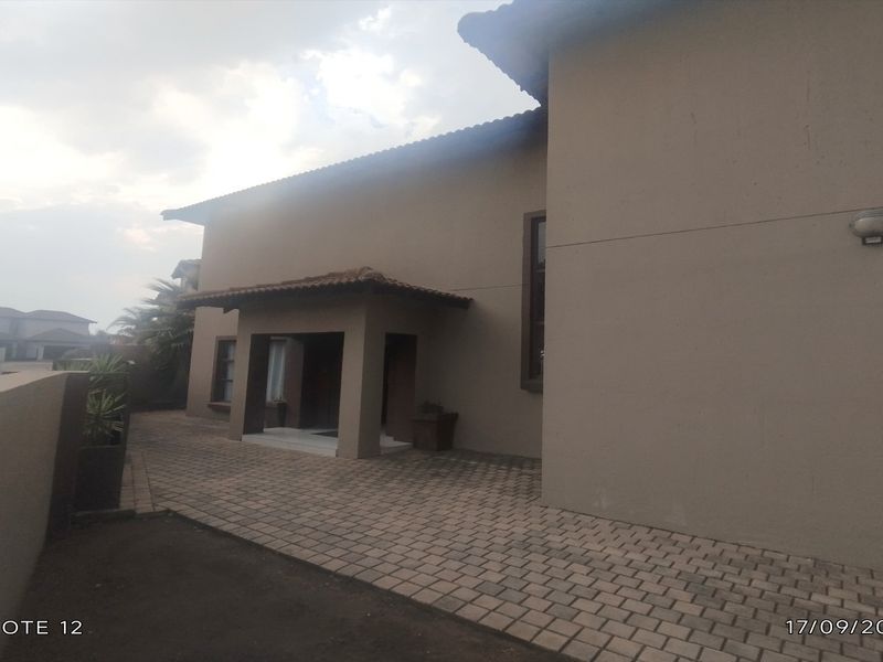 Front exterior view of the townhouse featuring a paved driveway and a covered entrance porch with neutral-toned walls.