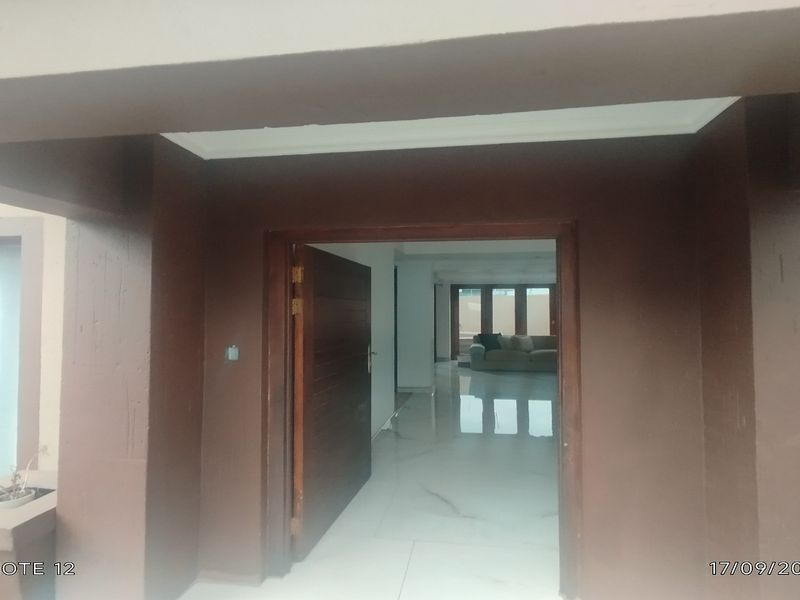 A covered entryway featuring a solid timber door and polished porcelain flooring, providing a clear view into the main living area of the townhouse.