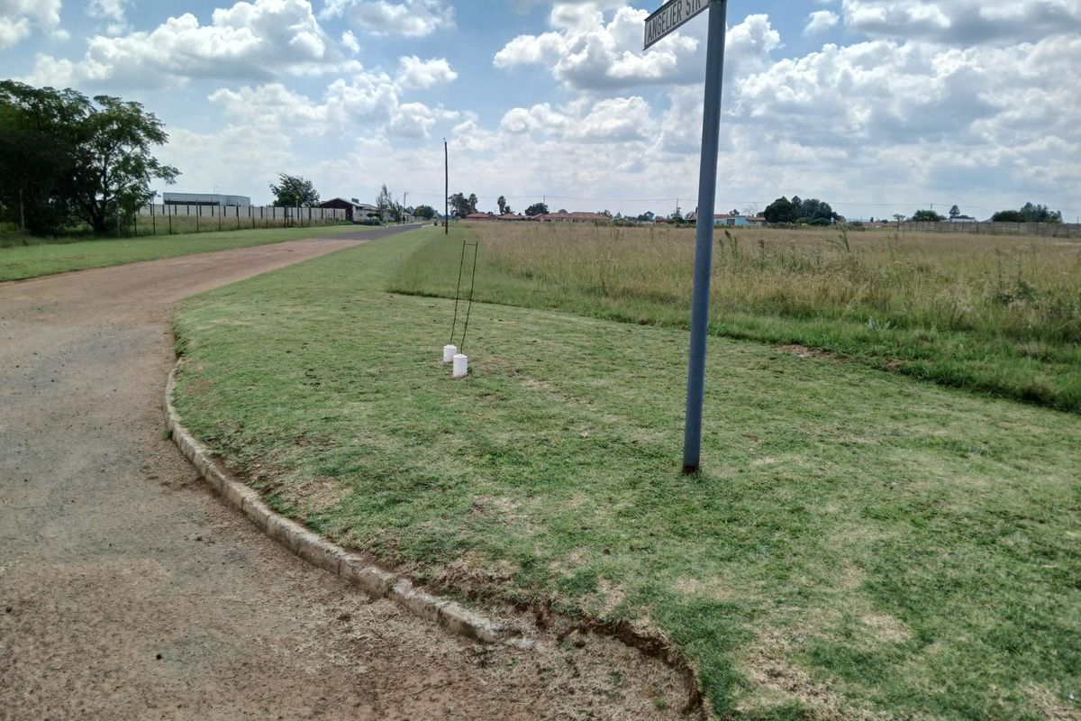 A street-level view of the vacant residential land, showing the corner plot, street signage, and access road.