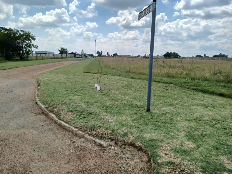 A street-level view of the vacant residential land, showing the corner plot, street signage, and access road.
