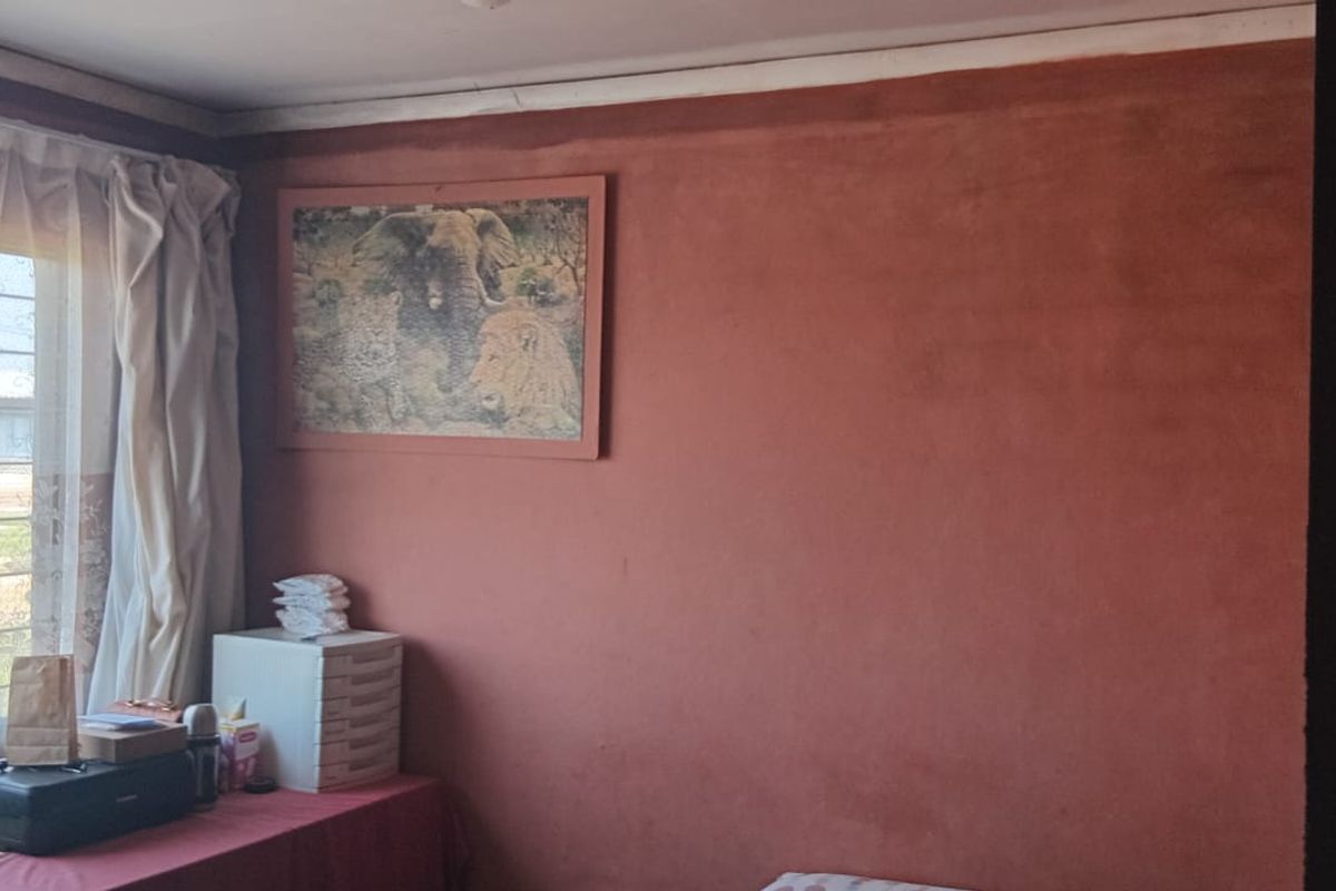 A bedroom featuring a sliding window and textured wall finish, requiring cosmetic updates to improve the overall aesthetic and condition.