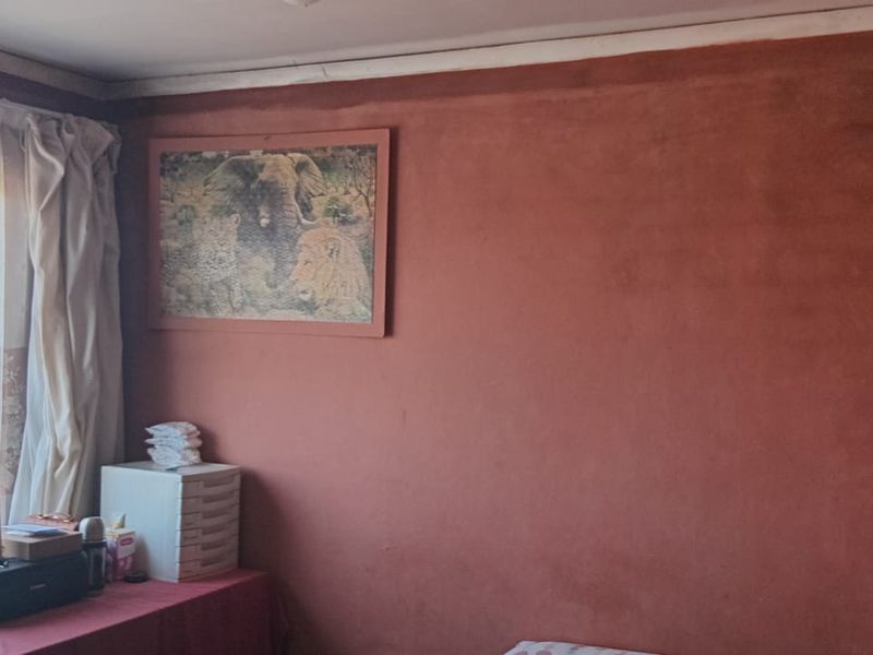A bedroom featuring a sliding window and textured wall finish, requiring cosmetic updates to improve the overall aesthetic and condition.
