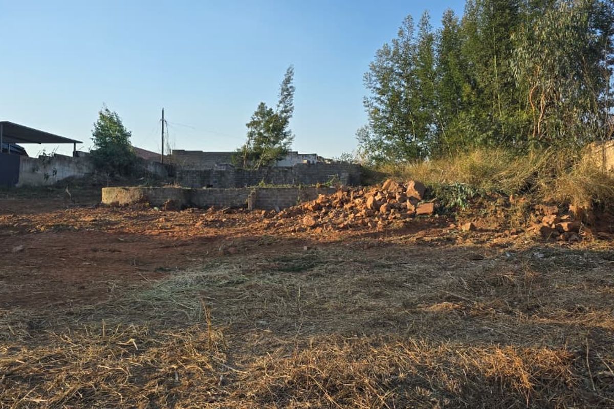 A vacant residential plot featuring perimeter brick walls, some retaining wall structures, and cleared ground ready for development.