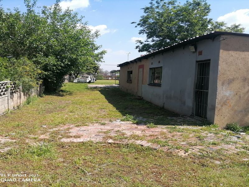 Rear view of the property showing a basic structure with a brick paved area and a concrete block boundary wall in need of maintenance.
