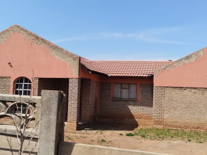 Front elevation of a single-story face brick house featuring a tiled roof, integrated garage, and perimeter boundary walling.