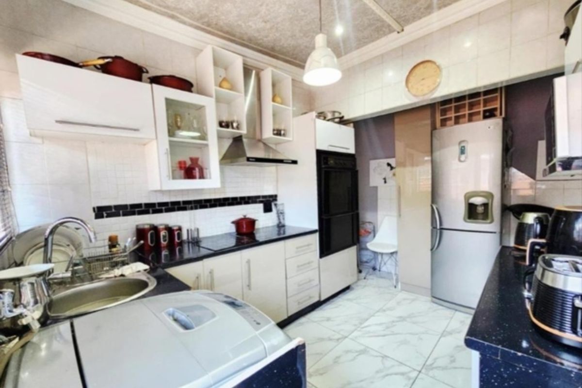 A functional kitchen featuring built-in cabinetry, a stainless steel extractor fan, integrated oven, and tiled finishes throughout.