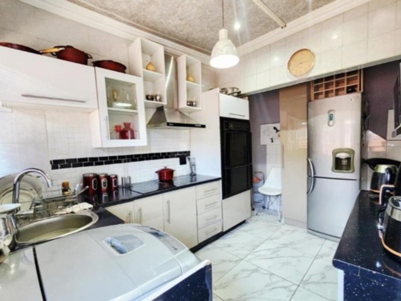 A functional kitchen featuring built-in cabinetry, a stainless steel extractor fan, integrated oven, and tiled finishes throughout.