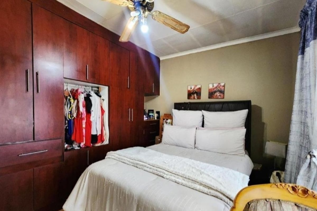 A bedroom featuring extensive dark wood built-in cupboards and a ceiling fan.