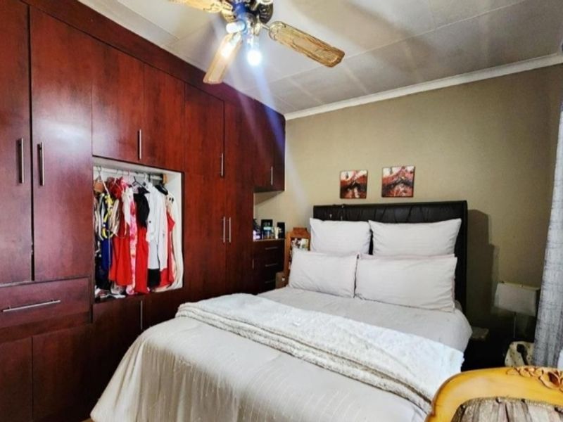 A bedroom featuring extensive dark wood built-in cupboards and a ceiling fan.