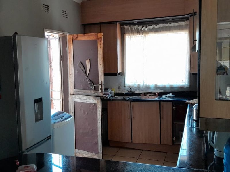 A functional kitchen featuring built-in cabinetry, granite countertops, and a double sink, offering potential for modernization and aesthetic updates.