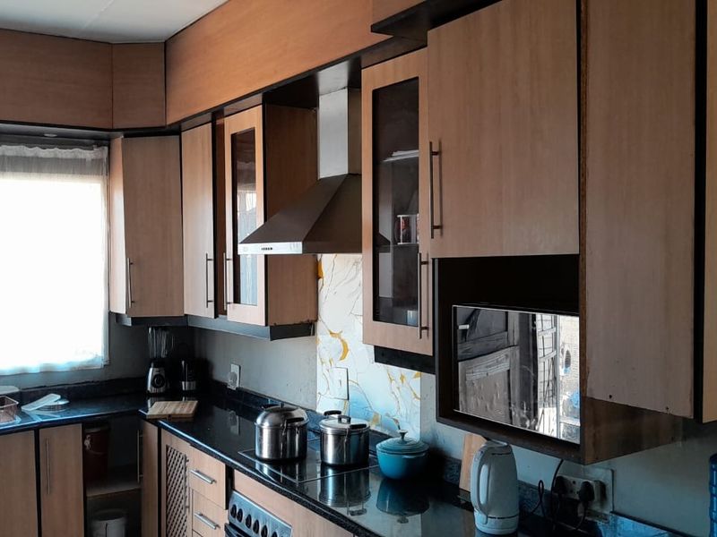 A functional kitchen featuring laminate cabinetry, granite countertops, a built-in oven, and a stainless steel extractor fan with a decorative glass splashback.