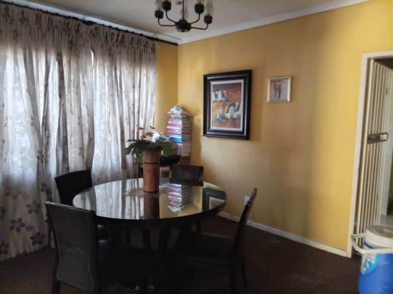 A dining room featuring yellow walls, carpeted flooring, and a central light fixture, providing a functional space for meals.