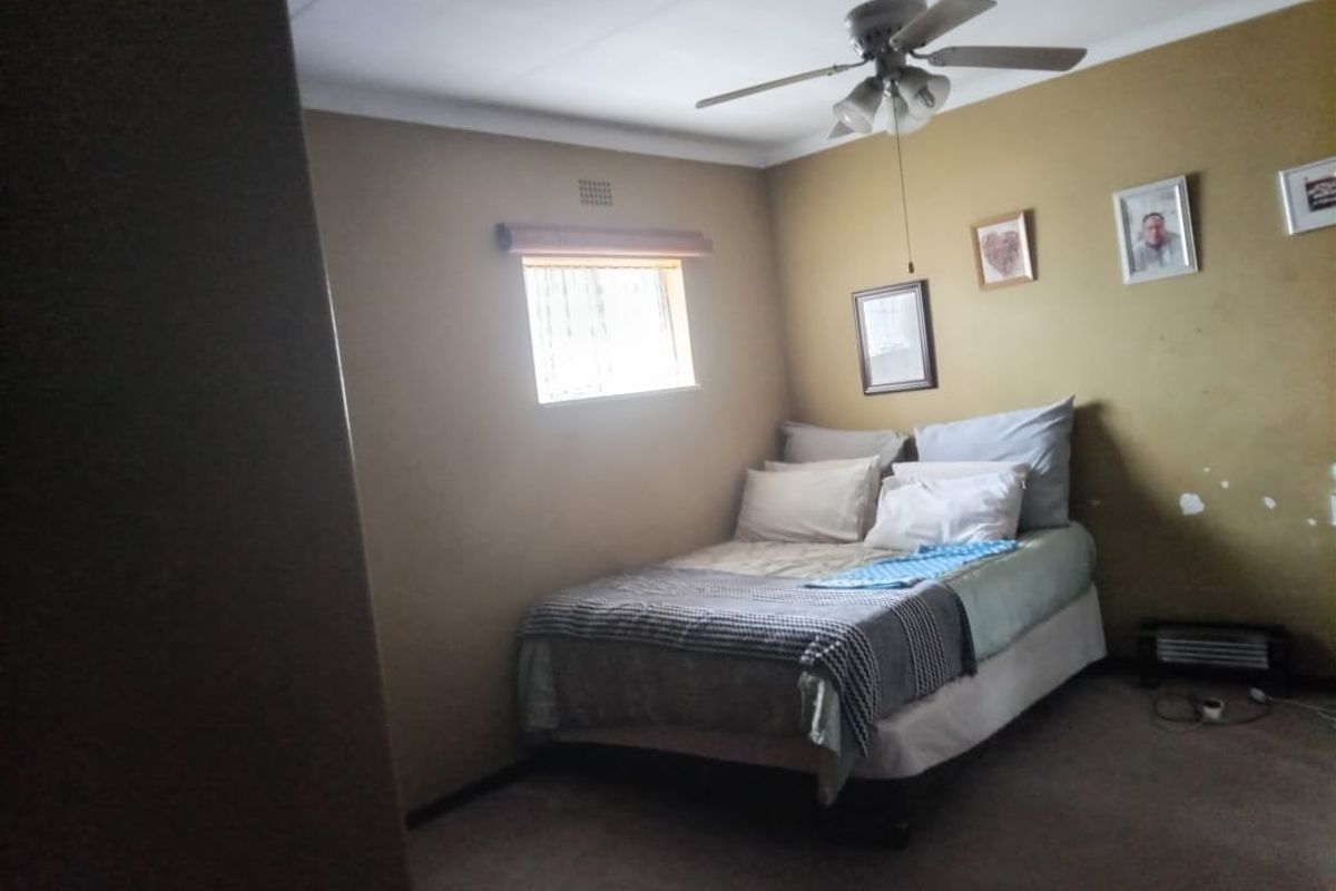 A bedroom featuring a ceiling fan, carpeted flooring, and neutral wall finishes, requiring minor cosmetic attention.