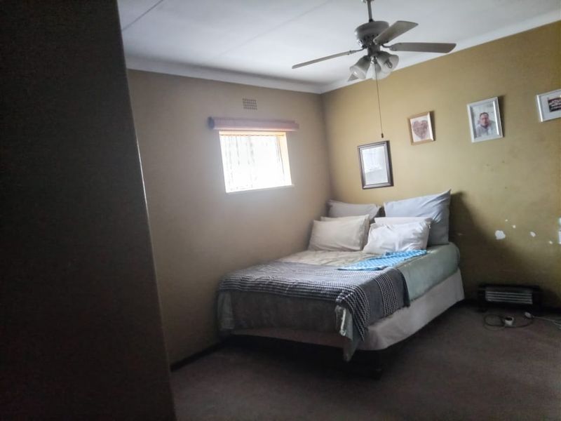 A bedroom featuring a ceiling fan, carpeted flooring, and neutral wall finishes, requiring minor cosmetic attention.