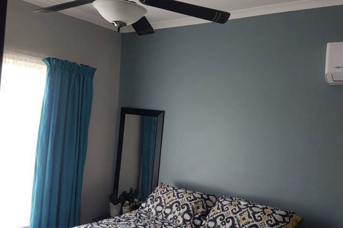 A well-maintained bedroom featuring a ceiling fan and a wall-mounted split-system air conditioning unit.