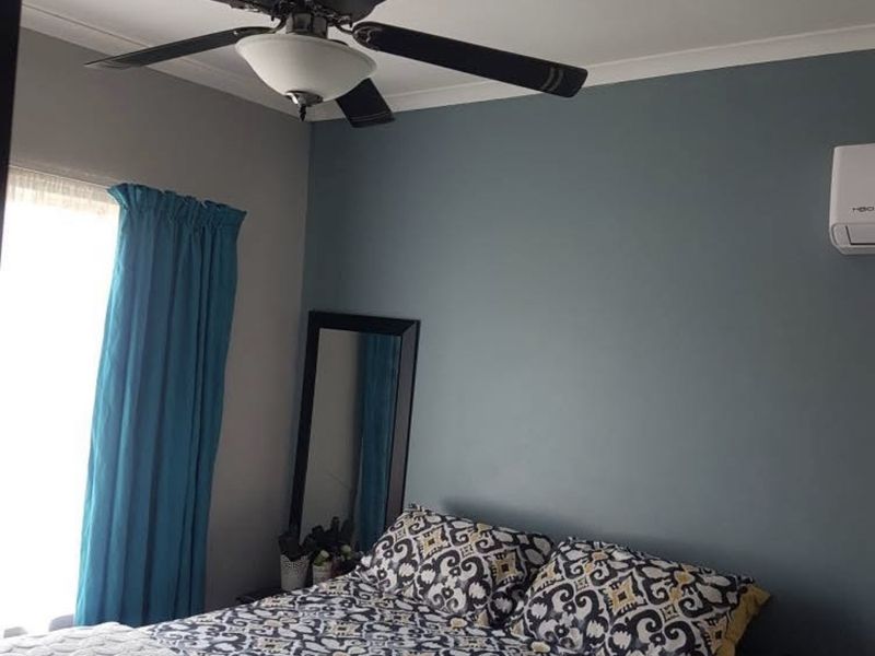 A well-maintained bedroom featuring a ceiling fan and a wall-mounted split-system air conditioning unit.