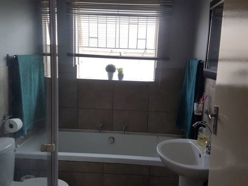 A functional bathroom featuring a bathtub, pedestal basin, toilet, and a separate shower enclosure with tiled wall finishes.