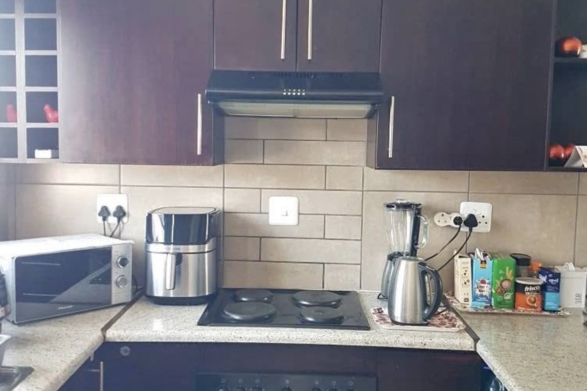 A functional kitchen featuring dark wood cabinetry, a subway tile backsplash, and integrated cooking appliances including an electric oven and hob.