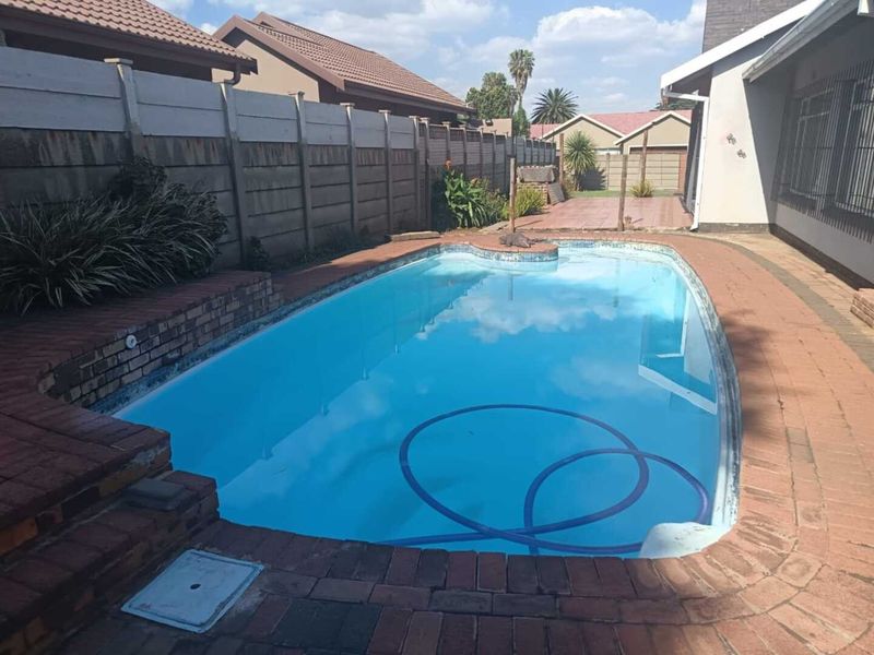 Outdoor swimming pool area featuring brick paving surround and precast concrete boundary walling.