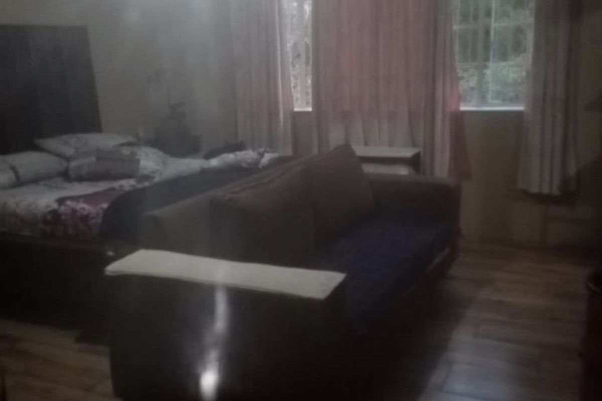 A bedroom featuring wood-look tile flooring and large windows that allow natural light into the space.