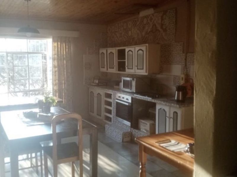 Open plan kitchen and dining area featuring a wooden ceiling, tiled flooring, and built-in cabinetry with a tiled backsplash.