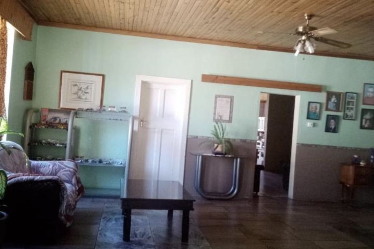 Spacious living area featuring a timber tongue and groove ceiling, ceiling fan, and tiled flooring throughout.
