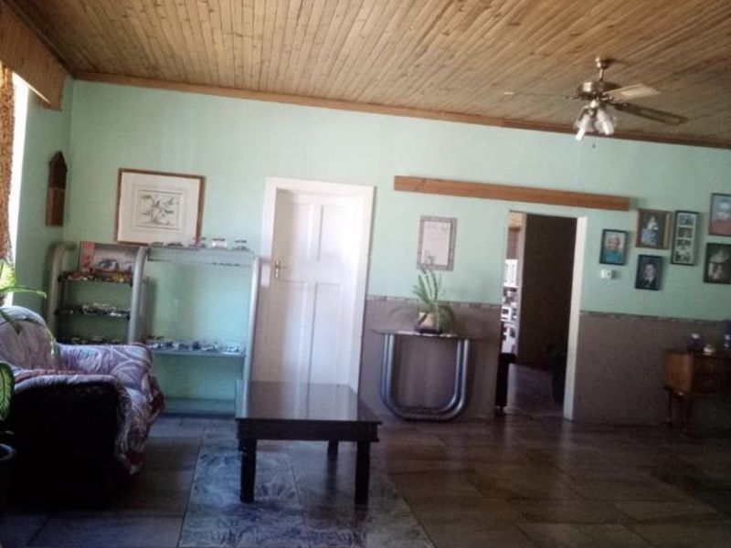 Spacious living area featuring a timber tongue and groove ceiling, ceiling fan, and tiled flooring throughout.