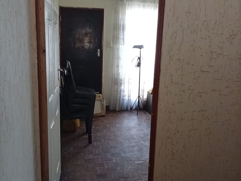 A bedroom featuring parquet flooring and textured wall finishes, viewed through a doorway.